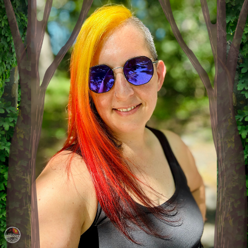 a woman with purple sunglasses, yellow to orange long hair on one side and shaved on the other, with a black tank top smiling